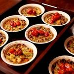Pasta displayed in multiple bowls, garnished with roasted grape tomatoes